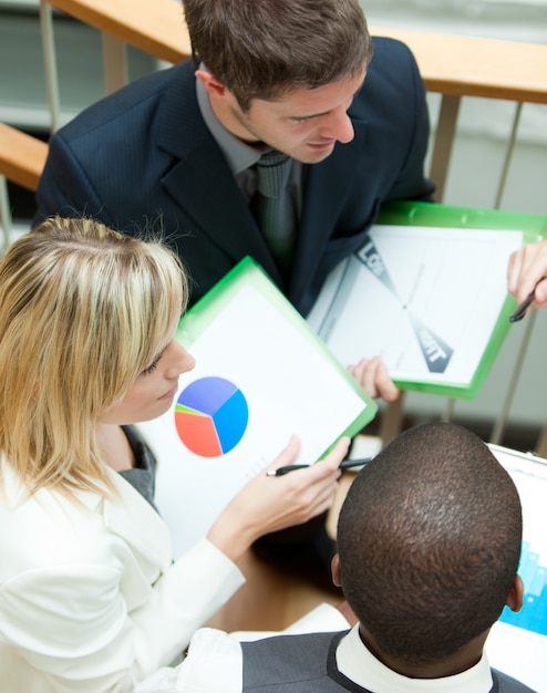 A photo of educational officials in a meeting discussing disciplinary policies, with data charts visible in the background, signifying the ongoing investigation.