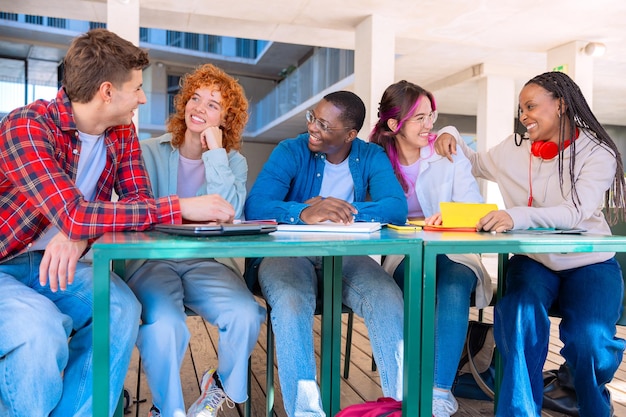 A diverse group of high school students sitting in a college classroom, actively participating in a lecture. The professor, visible in the foreground, is engaging with the students. The classroom setting is modern, with interactive whiteboards and comfortable seating.