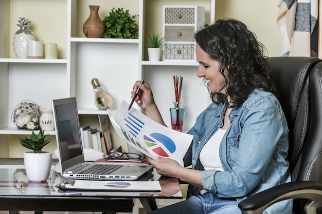 A person using a laptop at a desk, reviewing a detailed budget spreadsheet with categories such as income, expenses, savings, and investments, overlaid with graphs showing financial growth. This represents the active management of personal finances for retirement planning in the US.