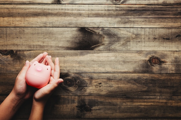 A person holding a coin over a piggy bank, symbolizing saving and financial planning. The background is a warm, inviting home setting with natural light.