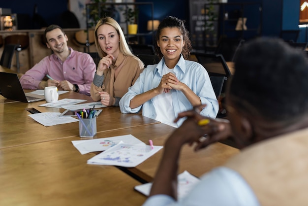 Diverse group of people engaged in a business negotiation, seated around a conference table. The atmosphere is collaborative, with open body language and engaged facial expressions.