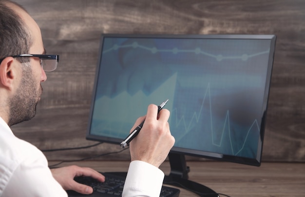 A person looking thoughtfully at a computer screen displaying complex data and charts related to student loan repayment plans. This image represents the analytical and planning aspects of managing student loan debt.