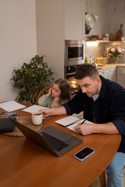 A parent and child reviewing financial documents together at a table, with a laptop displaying tax information. The scene suggests family, finances, and planning.
