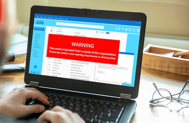 A close-up of a laptop screen displaying a warning message about a potential phishing scam. The message urges the user to verify their account details immediately.