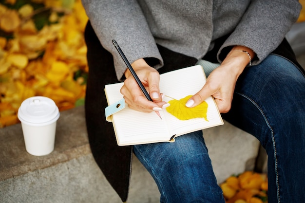 A person writing on a notepad, with a pen in hand, focusing intensely on their notes. The notepad is open to a page with bullet points and headings, suggesting careful planning and organization.