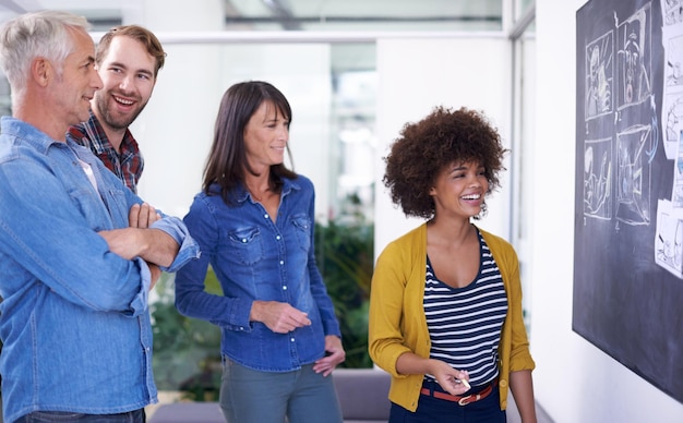 A group of diverse professionals collaborating in an open office space, smiling and engaged in a lively discussion around a whiteboard filled with ideas.