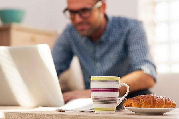A candidate is focused on completing an online assessment on a laptop, with a cup of coffee nearby. The setting is a bright and organized home office.