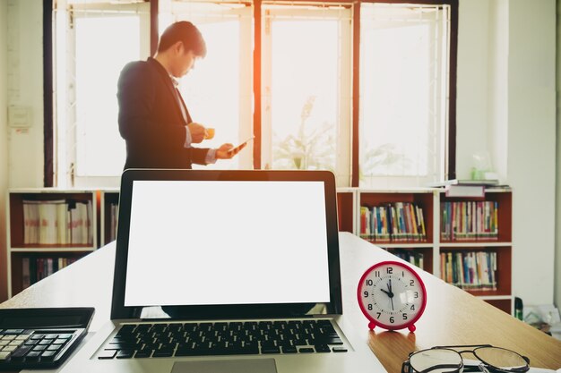A person sitting at a desk, working on a laptop. Their face is visible, showing engagement with a task. The background is a modern office space with books and motivational posters.