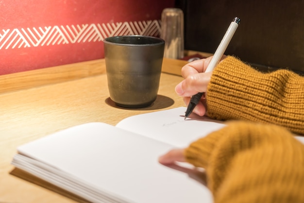 A close-up shot of a person writing in a notebook, outlining their goals for the 30-60-90 day plan. The background is slightly blurred, focusing on the pen and paper.