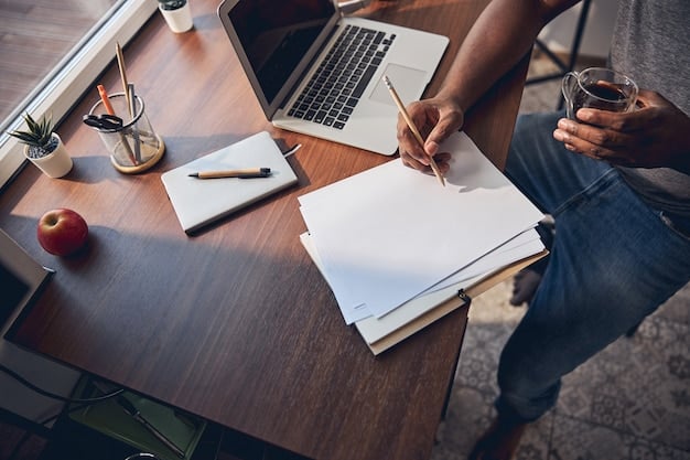 A person writing a letter at a desk with a laptop and various documents surrounding them.