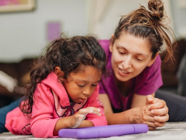 A close-up shot of a teacher engaging with a young child in a one-on-one activity, both smiling. The teacher is pointing to a picture book, fostering literacy skills and a love for reading in the child.
