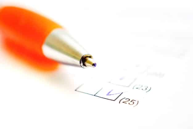 A close-up of the FAFSA form being filled out, with a pen hovering over a specific financial question. The background is blurred, focusing on the detailed section of the form.