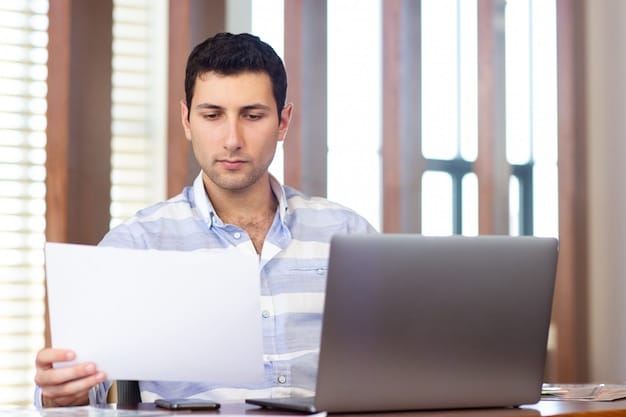 A person looking at a laptop screen, analyzing loan forgiveness program details, with documents scattered around.